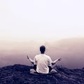 Man is doing Yoga pose on the rocks peak within misty morning Royalty Free Stock Photo