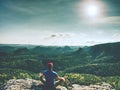 Man doing Yoga pose on the rocks peak within misty morning. Sportsman practices yoga at the top of the mountain at sunrise Royalty Free Stock Photo