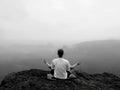 Man is doing Yoga pose on the rocks peak within misty morning Royalty Free Stock Photo