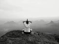 Man is doing Yoga pose on the rocks peak within misty morning Royalty Free Stock Photo