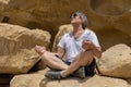 man doing yoga sitting on the rocks near the caves of Matala, Greece, Crete