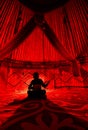 Man with dombra inside Yurt nomadic house with red lights