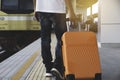 Man dragging orange suitcase luggage bag, walking in train station. Travel concept Royalty Free Stock Photo