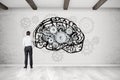 Man drawing brain on concrete wall with cogs Royalty Free Stock Photo