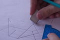 A man draws a diagram with a ruler, eraser and pencil. Design and create a project on a white sheet of paper close-up.