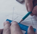 A man draws a diagram with a ruler, eraser and pencil.