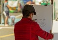 Man draws the portrait on white paper at the street.