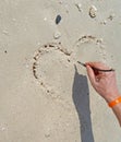 Sea sand on the beach with a drawing of heart on the sand as a gift favorite for Valentine `s Day. Royalty Free Stock Photo