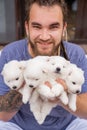 man with dreadlocks and beard holds puppies of four Japanese Spitz in his hands.