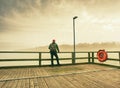 Man dreaming sitting on a wooden pier near the water Royalty Free Stock Photo