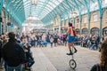 Man dress like clown riding wheelbarrow performing in the Covent Garden Market