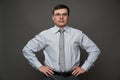 A man dressed as a businessman posing in a studio on a gray background, glasses, a light striped shirt and tie - casual office Royalty Free Stock Photo