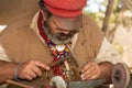 A man dressed as a copper smith from the 1800`s adds detail to a small piece of work with a hammer and awl Royalty Free Stock Photo