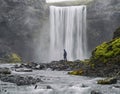 A man dressed in black standing at the base of a waterfall