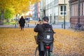 A man dressed in black stops with his bicycle to take photos of the fallen leaves and the yellow trees during autumn in MalmÃÂ¶,