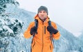 Man dressed bright orange softshell jacket with backpack have trekking on the winter mountains route. Active people or survival in Royalty Free Stock Photo