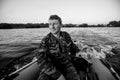 A man dressed in camouflage driving a motor rubber boat. Royalty Free Stock Photo