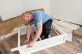 Man dressed casual assembling furniture in new house. Carpenter repair and assembling furniture at home