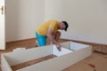 Man dressed casual assembling furniture in new house. Carpenter repair and assembling furniture at home