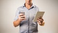 Man dressed casually in collared shirt using a tablet and phone Royalty Free Stock Photo