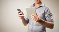 Man dressed casually in collared shirt using a tablet and phone Royalty Free Stock Photo