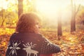 Man dressed in knit sweater with deers sitting on autumn leaves in park. Royalty Free Stock Photo