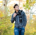 Man dressed in a plaid scarf walking in autumn park.