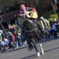 Man dressed in traditional cowboy clothing mounted on a horse and playing a guitar in the Scottsdale Parada Del Sol which is