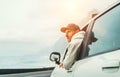 Man dressed warm hoodie and baseball cap driving his new car on the lonely road leading by the sea coast. Happy auto owner concept