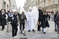 A man dressed in white angel clothes walks along Nikolskaya Street among the crowd