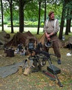 Man dressed in World War 2 British uniform with beret standing next to Machine gun and ammunition boxes