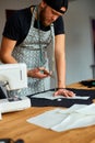 Man dressmaker cutting material with scissors on table, male tailor working in atelier