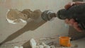 Man drilling round hole in concrete wall for socket. Builder drills hole with electric drill or perforator. Concept of