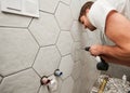 Man drilling wall with electric drill in bathroom at home. Royalty Free Stock Photo