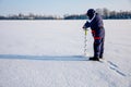 A man drills holes in the ice for ice fishing with an electric auger