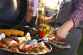 Man with drink cooking meat and vegetables on barbecue grill outdoors, closeup Royalty Free Stock Photo