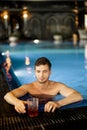 Man with a drink at swimming pool indoors Royalty Free Stock Photo