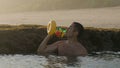 Man drinking beer from bottle with green glass as he is bathing ocean reef pool. Male person enjoying cold alcoholic Royalty Free Stock Photo