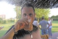 Man drinking beer in a outdoor bar. On background some friends enjoying. Beer in plastic glass