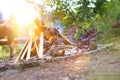 Man drinking beer while sitting on bench at park with bonfire Royalty Free Stock Photo