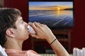 Man drinking a canned drink, beer or soda. On a TV screen watching the sunset on the river or sea. Concept of relaxation