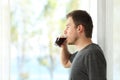 Man drinking coffee looking through window Royalty Free Stock Photo