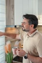 Man drinking coffee and opening blinds in a modern kitchen Royalty Free Stock Photo