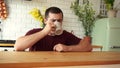 man drinking tea from a mug sitting at the table in the kitchen