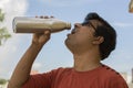 Man drinking water from bottle. Portrait of handsome young male In colorful t-shirt, drinking water from bottle On Blue Sky
