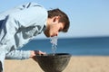 Man drinking water from a fountain on the beach Royalty Free Stock Photo