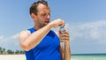 Man drinking water after running at beach. Thirsty sport runner Royalty Free Stock Photo