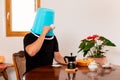 Man drinks coffee with a blue bucket on his head, flowers in the background Royalty Free Stock Photo