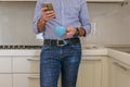 Man drinks a coffee in the kitchen and in the meantime looks at the smartphone Royalty Free Stock Photo