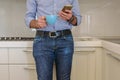 Man drinks a coffee in the kitchen and in the meantime looks at the smartphone Royalty Free Stock Photo